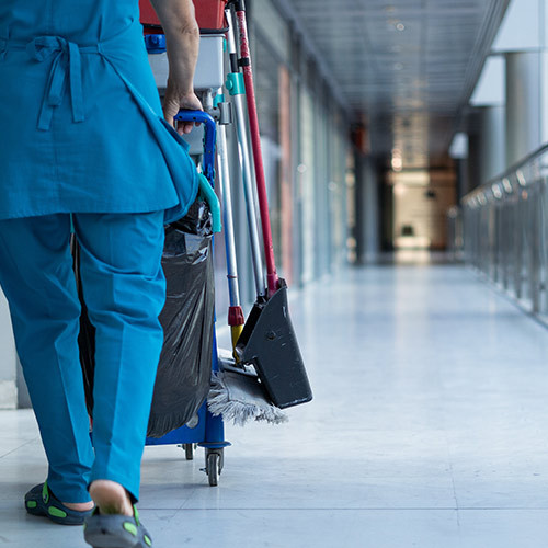 Reinigungskraft mit Wagen im Flur