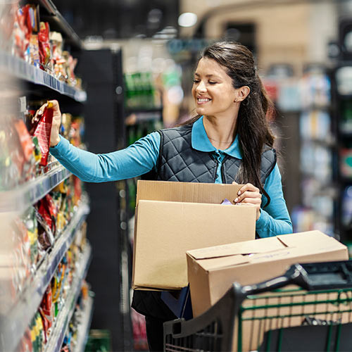 Frau räumt Regale ein im Supermarkt
